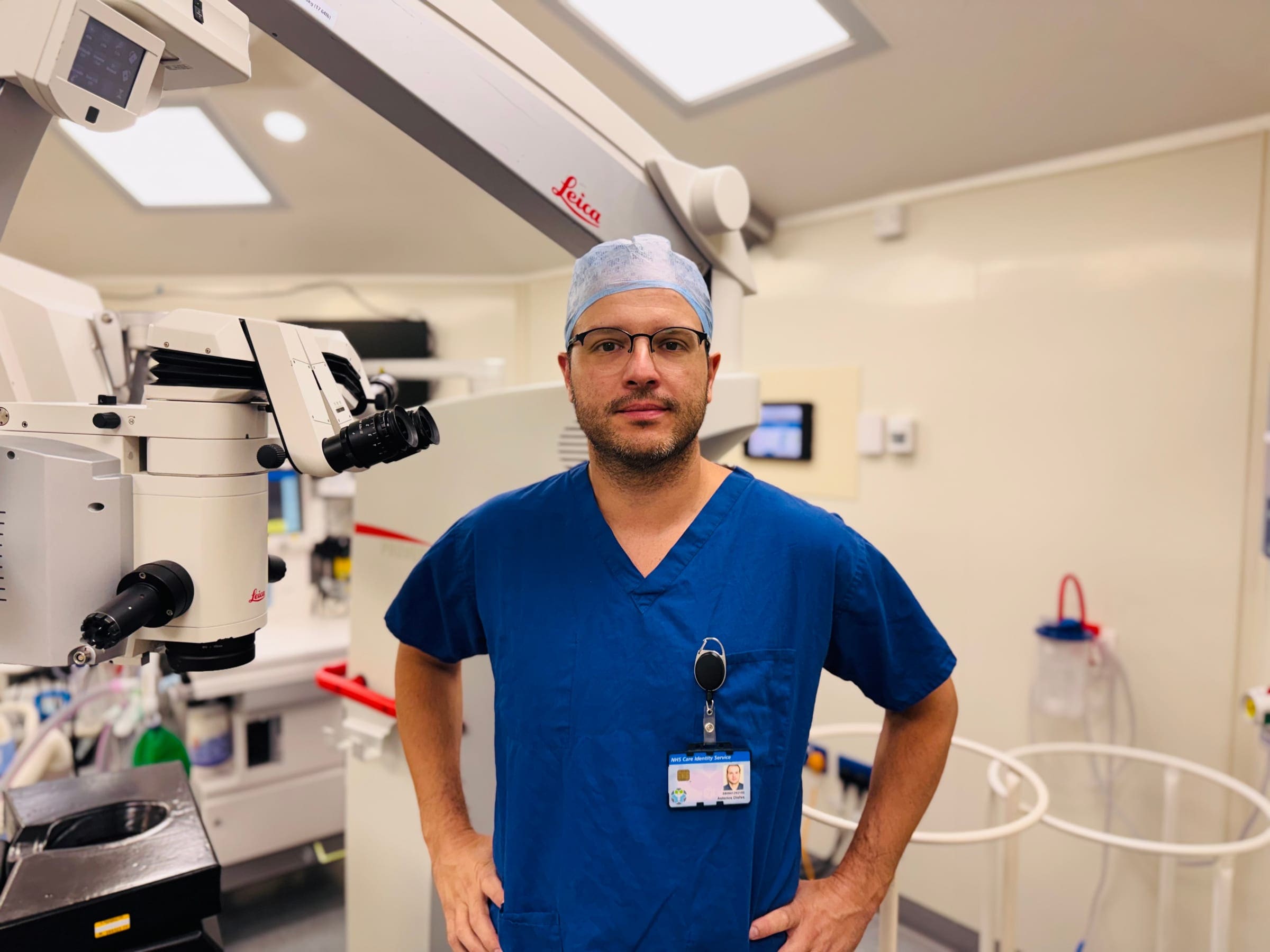 Dr. Diafas in the operating theatre, beside a surgical microscope.